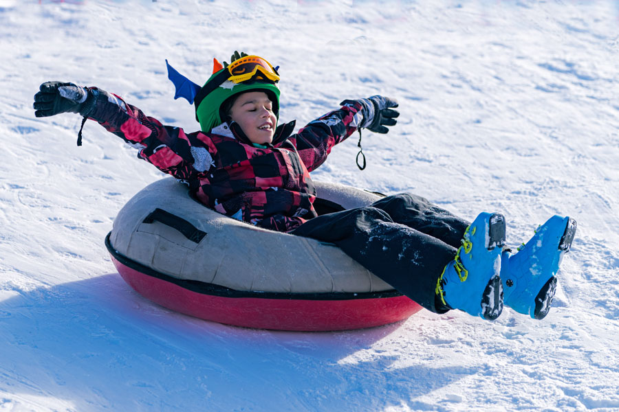 boy riding tube down snowy hill