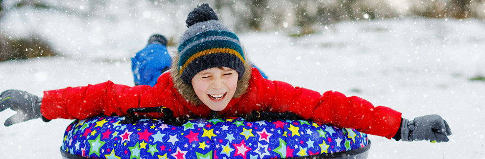 child sliding on tube in the snow